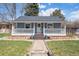 Charming blue home featuring a welcoming front porch, stone pathway, and landscaped yard at 4190 S Grant St, Englewood, CO 80113