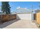 Detached garage featuring a large white door and light blue siding, along a wood fence at 4190 S Grant St, Englewood, CO 80113