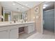 Well-lit bathroom with double vanity, large mirror, framed art and an enclosed shower area at 5751 E Ithaca Pl # 3, Denver, CO 80237