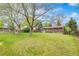 Spacious backyard with lush lawn, mature trees, patio, and playground area, ideal for relaxation and recreation at 7034 S Cherry St, Centennial, CO 80122