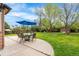 Spacious backyard with patio, umbrella, seating, lush green lawn, and play set at 7034 S Cherry St, Centennial, CO 80122
