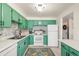 Bright kitchen featuring green cabinets, white appliances, mosaic backsplash, and a colorful area rug at 7034 S Cherry St, Centennial, CO 80122