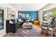 Bright living room with a blue accent wall, plush seating, and a large bay window at 7034 S Cherry St, Centennial, CO 80122