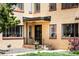 Apartment entrance with a brick facade, black trim, and maintained front yard with lawn and mature tree at 1160 Birch St # 22, Denver, CO 80220