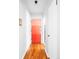 Hallway with hardwood floors, white trim, and bright orange apartment front door at 1160 Birch St # 22, Denver, CO 80220