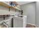 Laundry room with modern appliances, wood-look flooring, and practical shelving above at 12988 E 108Th Pl, Commerce City, CO 80022