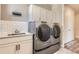 Well-equipped laundry room with modern washer and dryer, ample storage, and subway tile backsplash at 4955 N Picadilly Ct, Aurora, CO 80019