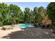 Backyard with an outdoor fireplace and a pool with a spa, surrounded by lush greenery at 5550 Preserve Dr, Greenwood Village, CO 80121