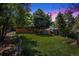 Beautifully landscaped backyard with lush green grass, mature trees, and a charming storage shed at dusk at 3647 S Uravan St, Aurora, CO 80013