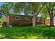 Quaint brick home featuring a lush green lawn and mature trees offering shade and privacy at 6088 Quail Ct, Arvada, CO 80004