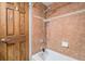 Bathroom featuring wood door, neutral tub and shower with neutral brown tiles at 7865 E Mississippi Ave # 1102, Denver, CO 80247