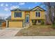 Charming two-story home with a bright yellow exterior, blue trim, and a two-car garage at 10241 Routt St, Broomfield, CO 80021