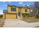 Charming two-story home with a bright yellow exterior, blue trim, and a two-car garage at 10241 Routt St, Broomfield, CO 80021