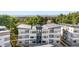 An aerial view shows the modern condo buildings surrounded by lush trees, neighborhood and mountain views at 1308 Snowberry Ln # 303, Louisville, CO 80027