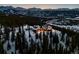 Stunning aerial view of a mountain chalet nestled amongst trees in a snowy landscape and ski resort in the background at 300 Little Sallie Barber Trl, Breckenridge, CO 80424