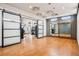 Spacious gym area with mirrors, barn doors, unique lighting, and wood floors at 9162 Star Streak Cir, Littleton, CO 80125