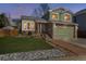 Charming two-story home featuring a stone facade, green siding, well-maintained lawn, and a two-car garage at 13199 Ash St, Thornton, CO 80241