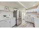 Bright kitchen featuring stainless steel refrigerator, white cabinets, subway tile backsplash and modern countertops at 3275 S Decatur St, Denver, CO 80236