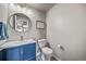 Modern half-bathroom with a pop of color vanity, unique flooring, and a round mirror at 17382 Bluetrail Ave, Parker, CO 80134