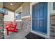 Cozy front porch with stone accents, a blue front door, a doormat, and two red Adirondack chairs at 17382 Bluetrail Ave, Parker, CO 80134