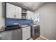 Well-organized laundry room with modern washer and dryer, cabinets and striking blue patterned backsplash at 17382 Bluetrail Ave, Parker, CO 80134