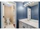 Stylish blue bathroom with white tile flooring, a modern vanity, and a large mirror with lighting at 19281 E Hinsdale Ln, Centennial, CO 80016