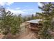 Aerial view of a charming house with a covered deck surrounded by a forest and mountain views at 13012 S Wamblee Valley Rd, Conifer, CO 80433