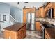 Spacious kitchen with stainless steel refrigerator, wood cabinets, island, and staircase to second floor at 9677 Castle Ridge Cir, Highlands Ranch, CO 80129