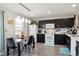 Eat-in kitchen featuring dark cabinets, white appliances, and a modern glass-top table at 765 Mockingbird St, Brighton, CO 80601
