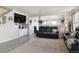Bright living room with gray wood floors, a large black leather sofa, and decoratively-adorned wall at 765 Mockingbird St, Brighton, CO 80601