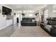 Open-concept living room with gray wood floors, a large black leather sofa, and plenty of natural light at 765 Mockingbird St, Brighton, CO 80601