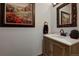 Charming powder room with decorative mirror, framed artwork, and a wood vanity with white countertop at 31332 Island Dr, Evergreen, CO 80439