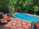 Backyard in-ground pool surrounded by lush greenery and a vibrant outdoor rug at 2492 S Yarrow St, Lakewood, CO 80227