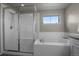 Bright bathroom with tiled shower, glass door, and soaking tub beneath a window at 8695 Torrey St, Arvada, CO 80007