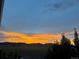 A fiery sunset lights up the horizon, viewed from a deck of the property at 8695 Torrey St, Arvada, CO 80007