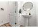 Clean powder room featuring a pedestal sink, round mirror, and modern fixtures at 19 S Harrison St, Denver, CO 80209