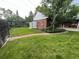 Lush backyard featuring mature trees, manicured lawn, stone pathway, brick exterior, and storage shed at 701 S Clayton St, Denver, CO 80209