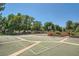 Outdoor tennis and basketball court surrounded by mature trees on a sunny day, perfect for recreation at 5995 E Iliff Ave # 106, Denver, CO 80222