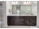 Bright bathroom features dual sinks with dark cabinetry and a large mirror at 11027 Sunshimmer Cir, Parker, CO 80134