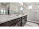 Bright bathroom features dual sinks with dark cabinetry and a walk-in shower at 11027 Sunshimmer Cir, Parker, CO 80134