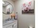 Charming powder room features marble countertops, a decorative mirror, and a playful pig portrait at 9676 W Chatfield Ave # B, Littleton, CO 80128