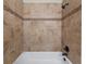 Tiled shower with a white tub and brown accents at 9676 W Chatfield Ave # B, Littleton, CO 80128