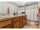 Well-lit bathroom with double sinks, ample counter space, wood cabinets and a shower with a white curtain at 10961 Main Range Trl, Littleton, CO 80127