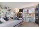 Bright bedroom with a TV, desk, comfortable bedding and decoratively arranged shelves with books and keepsakes at 10961 Main Range Trl, Littleton, CO 80127