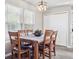 Charming dining room with wood table, six chairs, a modern light fixture, and two windows at 10961 Main Range Trl, Littleton, CO 80127