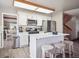 Eat-in kitchen features white cabinetry, a center island, and stainless appliances; the adjacent stairway leads upstairs at 10961 Main Range Trl, Littleton, CO 80127
