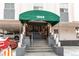 Building entrance with a green awning, steps, and a view of the parking area at 1265 Race St # 408, Denver, CO 80206