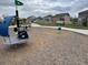 Community playground with play equipment in a wood chip safety area, next to a sidewalk and green lawn at 6711 Fraser Cir, Frederick, CO 80530