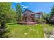 Beautiful backyard with deck, lush green grass, and mature trees at 10358 Kelliwood Way, Highlands Ranch, CO 80126
