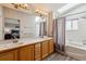 Bright bathroom featuring a double vanity, shower-tub combo, and a skylight at 10358 Kelliwood Way, Highlands Ranch, CO 80126